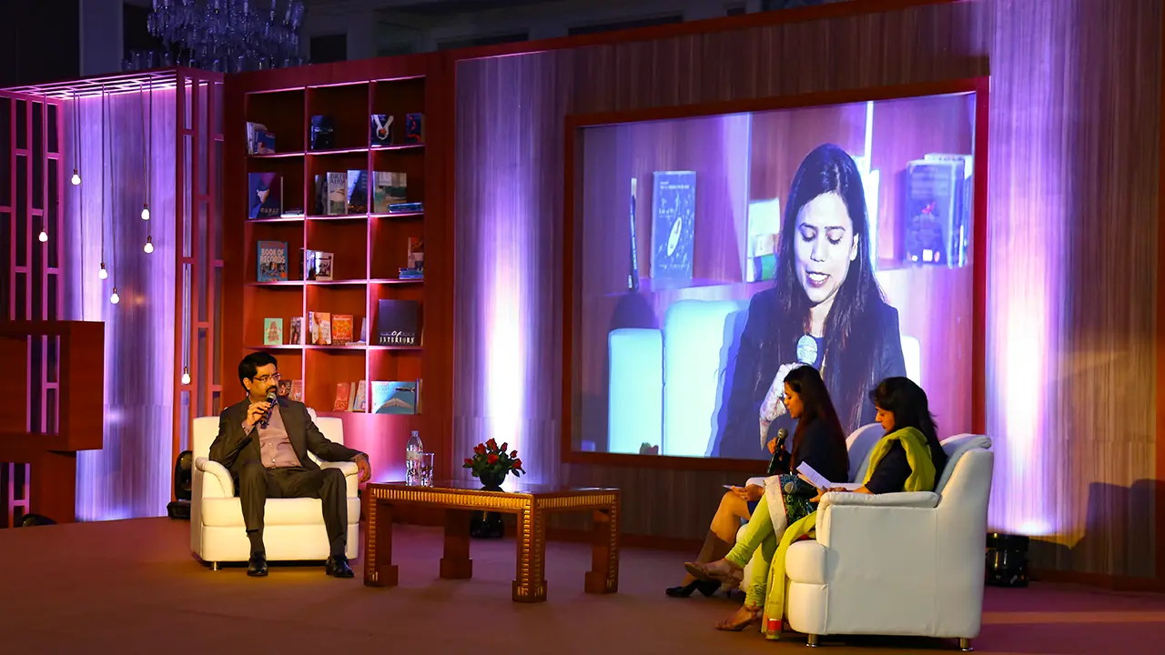 Fireside chat with Aditya Birla Group Chairman in an intimate, bookshelf-themed stage set with live projection and relaxed audience dialogue format