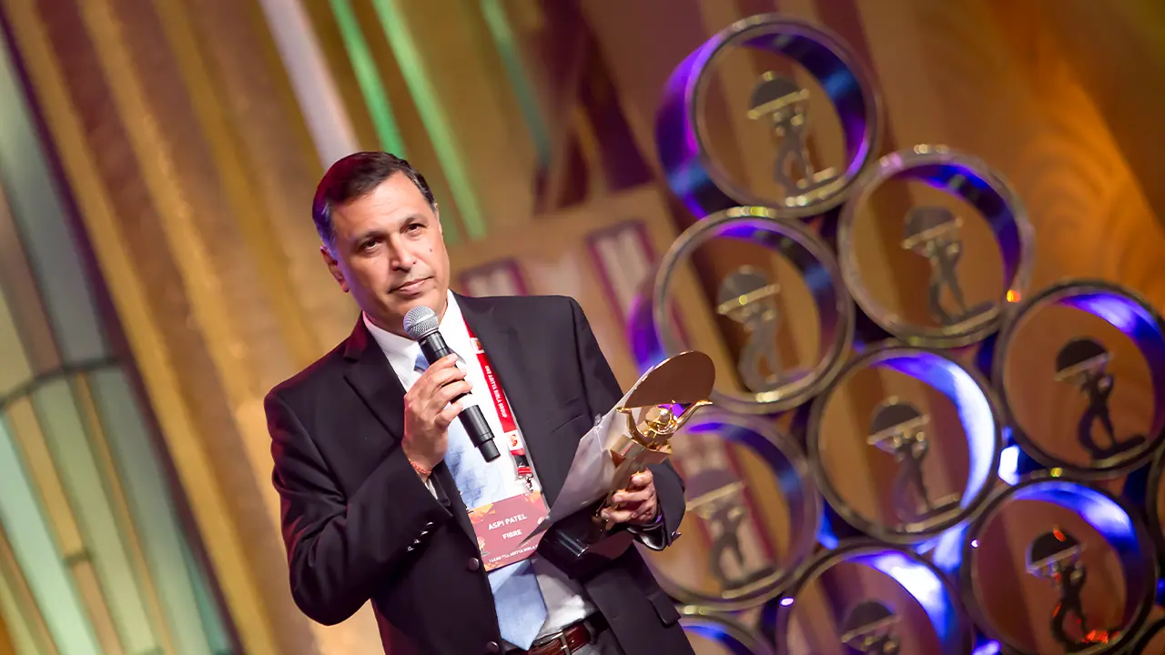 Award recipient onstage at ABG Awards, with a custom-designed Art Deco backdrop and branded trophy display enhancing visual storytelling and brand prestige