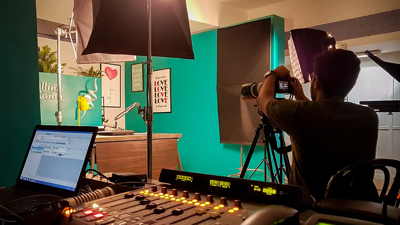 Calling Karan Season 2 studio setup with teal walls, desk mic, quote posters, and cinematographer framing the shot