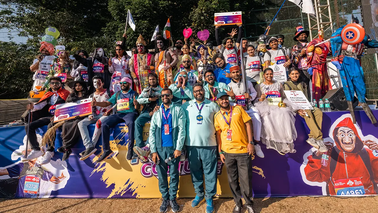 Costumed runners celebrating at the TCS World 10K Bengaluru Run In Costume (RIC) event, a Procam International sub-IP celebrating creativity, community, and social messaging through themed attire