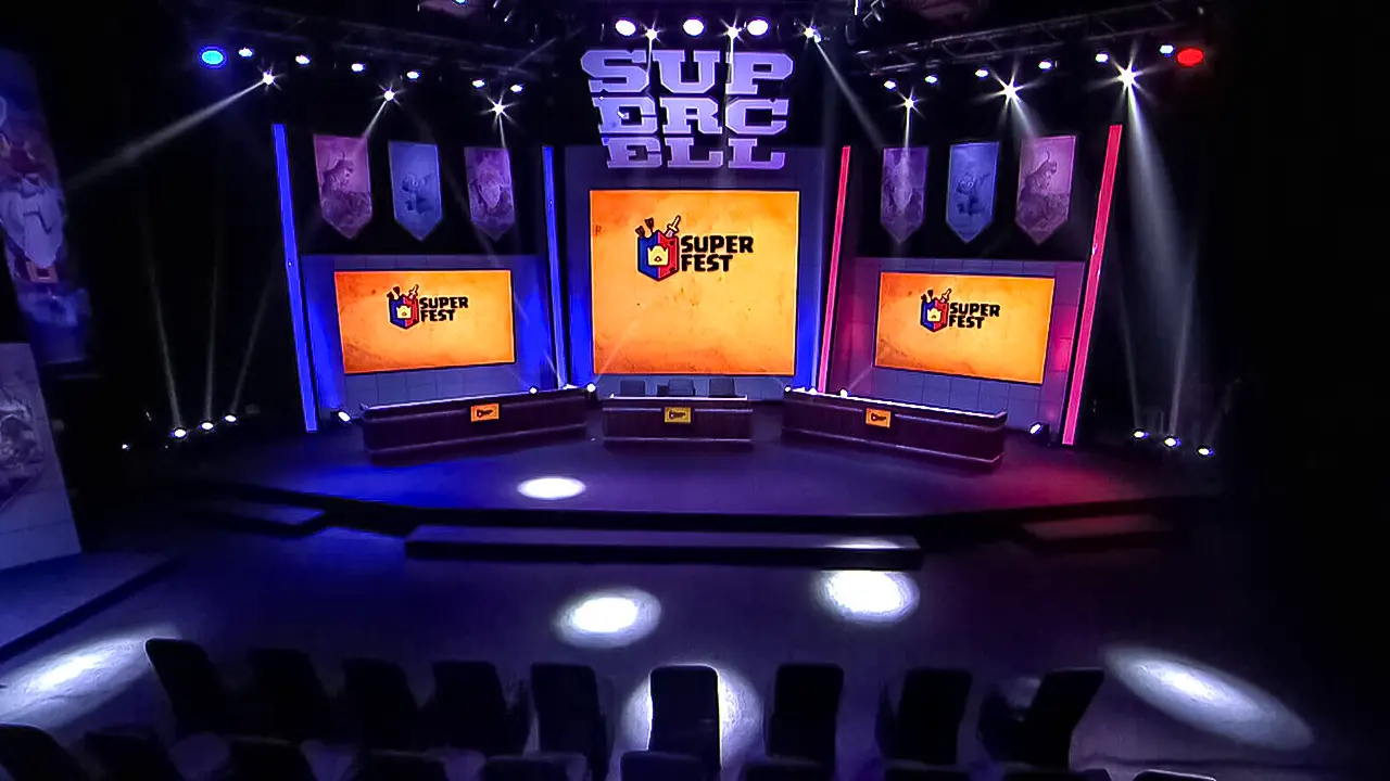 Supercell #SuperFest tournament stage with triple-screen game branding, team desks and arena lighting pre-show